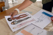 © Wavebreak Media - Sheet of fashion sketches occupying center of beige cloth worktable, with scissors and ruler nearby