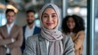 © 69 - Confident young woman in headscarf standing with diverse business team in modern office, smiling professional female leader portrait