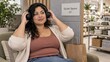 © gn8 - Latina shopper adjusting her headphones during a seated break in a homeware store rest alcove with a Quiet Space sign and acoustic panels for sensory friendly shopping