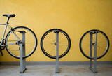 Sustainable transportation and urban mobility, bicycle parking rack with wheels in a row against a yellow wall for eco friendly city commuting
