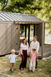 © BGStock72 - Family stroll by the modern cabin in a serene outdoor setting near water