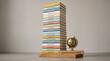© Muhammad - A tall stack of colorful hardcover books with a small brass globe on a wooden base with educational labels stands stands beside intelligence intellectual exploration