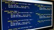 © abdul - Computer monitor displaying repeating lines of source code on a dark blue screen background