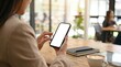 © Working Moments - A professional woman holding a smartphone with a white blank screen in a cafe setting.
