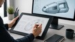 © Tati - Designer sketching a futuristic vehicle concept on a graphics tablet with a stylus, while a 3D model appears on a monitor in a modern desk workspace