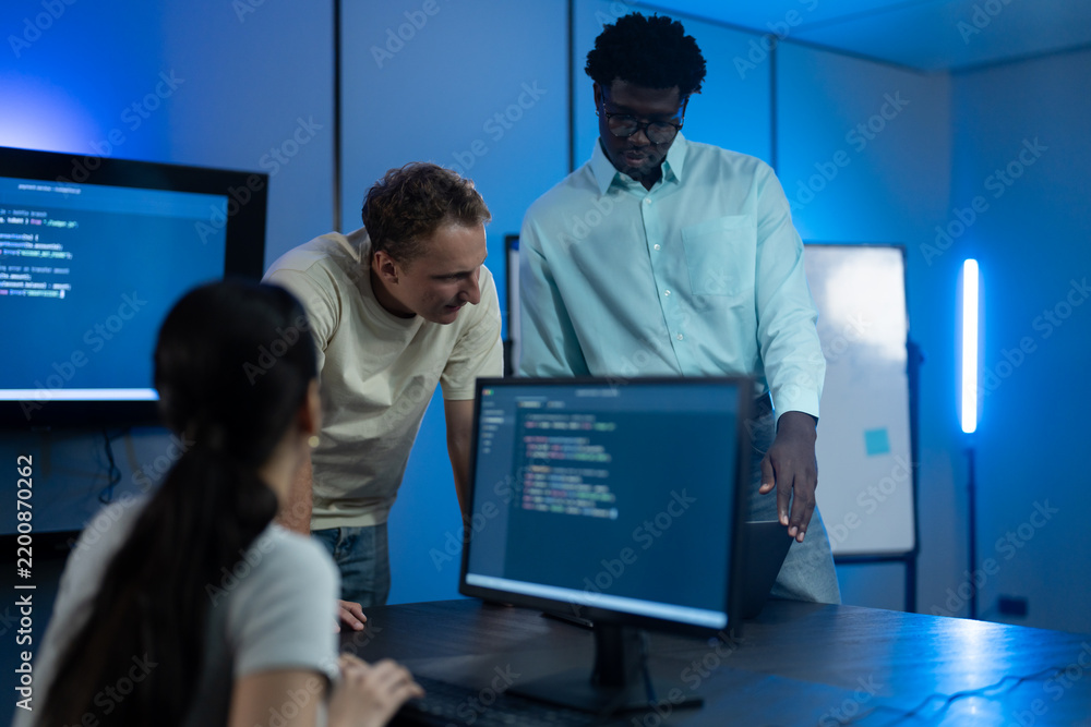 Diverse software developer team analyzing code on large monitors in ...