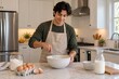 © Jafree - Latino man mixing pancake batter in modern kitchen with ingredients on marble countertop. concept of cooking, home baking, culinary hobby