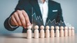 © Abu - Business manager placing a wooden figure in a lineup to represent team management and human resources