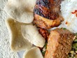 © yusuf - Delicious Indonesian grilled chicken meal with fragrant steamed rice, savory tempeh, fresh vegetables, and crispy crackers, offering a delightful authentic Asian culinary experience