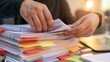 © AZ Studio - Hands flipping through a thick stack of organized business documents with colorful sticky tabs