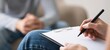 © oksa_studio - Therapist taking notes during counseling session with patient in blurred background