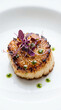 © airanxza - A perfectly seared jumbo scallop served on a white plate with microgreens and herb oil.