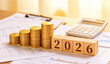 © good-J - An image related to economics featuring 2026 objects and a pile of coins placed on top of various documents and a calculator