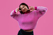 © oneinchpunch - Young woman showing rock n roll gesture smiling