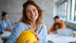 © Pinklife - A confident woman smiling while holding a yellow hardhat in a contemporary construction office, showcasing empowerment in traditionally male-dominated professions.
