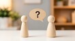 © Pixels Stock - Two wooden figures facing each other with a speech bubble containing question mark symbolizing communication or query.