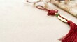 © Heyocha - Red tassel ornament with golden coins and intricate knot placed on beige textured background with scroll for festive cultural celebrations