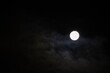 © syntheticmessiah - Midnight sky background. A bright white full moon glowing in a dark night sky. Thin clouds drifting across the sky around the bright lunar disc