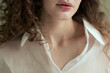 © Elena Kharichkina/Stocksy - Close up Woman with curly hair in white shirt posing indoors