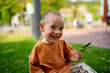 © Raul Navarro/Stocksy - Happy smiling boy playing with a daisy in park