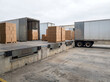 © uiminhaj - Open freight containers and stacked cartons at a concrete loading dock