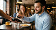 © Bandit - Man paying with a contactless credit card at a restaurant with his partner