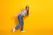 © deagreez - Cheerful young woman in trendy summer attire posing joyfully on a vibrant yellow background
