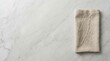 © SunSpirit - A folded beige linen napkin resting on a light gray marble table surface.