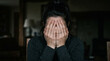 © Malo - Grieving woman covering her face with her hands in a dark room