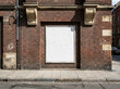 © Xisxas - An empty blank promotional poster frame mounted on an aged red brick exterior wall in a European city street, creating a versatile placeholder for urban advertising campaigns and media displays