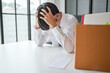 © Charlie's - Asian Businessman Touching Forehead with Headache at Office Desk Experiencing Burnout Stress and Emotional Pain from Boring Job.