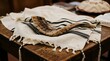 © Sain - Jewish shofar horn rests on white tallit prayer shawl. Traditional ritual objects for Rosh Hashanah, Yom