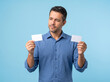 © Douglas Barbosa - Thoughtful mature man holding two blank white cards making a choice between payment options on blue background