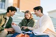 © Breezze - Students using a laptop on pale green campus steps, chatting with relaxed energy for education and digital learning campaigns