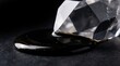 © Lucian - Macro shot of a faceted diamond crystal touching a pool of thick black oil with shimmering gold dust particles on a dark textured background