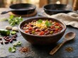 © EverFrame Studio - Bowl of hot chili con carne with red beans and melted cheese served on a dark stone table. chili cookoff