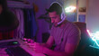 © Krakenimages.com - Man wearing headset holds gamepad and smartphone, tapping the screen with focused hands in a streaming studio; concentration.
