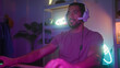 © Krakenimages.com - Man wearing headset and t shirt waves hand over keyboard and grips gamepad while gaming and streaming in a studio; competitive focus.