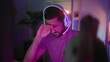 © Krakenimages.com - Man wearing white headset rubs eyes with hand while holding gamepad in gaming studio lit by purple led lights; fatigue.