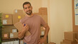 © Krakenimages.com - Man holding clipboard with hand on hip among packed boxes in a small business building; pride entrepreneurship.