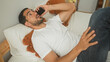 © Krakenimages.com - Man lying on bed holding smartphone to ear in bedroom, wearing white t shirt and jeans, hand on chest, occasionally resting arm behind head, smiling while talking; relaxed connection.