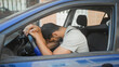 © Krakenimages.com - Man leaning with head on steering wheel in parked car on street, hands clasped on wheel; fatigue stranded commute.