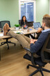 © David Pereiras - Rear view of seated man resting feet on shared desk as colleague smiles across their office. Informal break concept emphasizing belonging, friendly culture and relaxed social interaction.