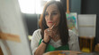 © Krakenimages.com - Woman painter in apron holds paintbrush to canvas while balancing palette in a studio; quiet concentration.