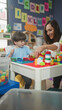 © Krakenimages.com - Woman and little boy play with colorful building blocks at a table inside a building, hands pointing and stacking bricks; playful learning.