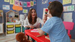 © Krakenimages.com - Woman leaning forward smiling helps little boy hold mallet and play xylophone in preschool classroom; joyful learning.