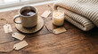 © Toshi - Steaming cup of black coffee beside a cozy wool sweater and glowing candle on rustic wooden table