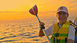 © wkproduction - A smiling woman enjoying a sea kayaking adventure during sunset, wearing a life vest and holding a paddle. This vibrant scene captures an active lifestyle and recreational pursuit on the tranquil sea.