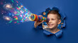 © ZaStock - Happy young boy looking through colorful toy telescope peering through torn blue paper, magic galaxy and stars emerging from lens. Imagination, childhood, astronomy, science education.