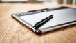 © Muhammad - Digital graphics tablet with stylus pen resting on a wooden desk surface with copy space